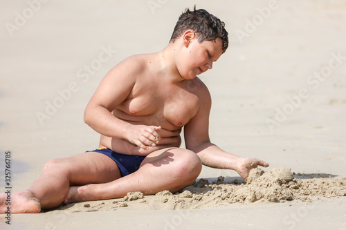 A boy plays in the sand on the seashore