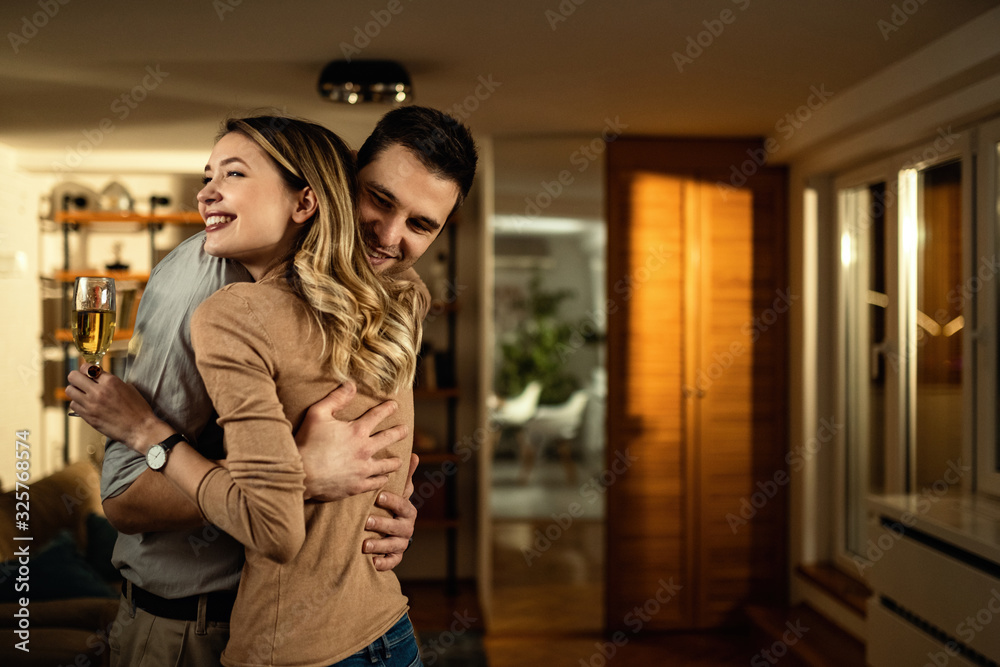 Young happy couple embracing in the evening at home.