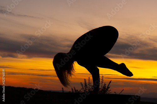 Fototapeta Naklejka Na Ścianę i Meble -  Silhouette woman coach yoga practice at sunset. Crane, crow pose. Bakasana