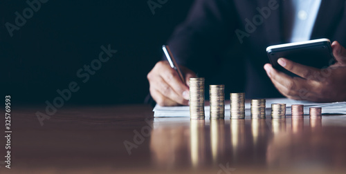 businessmen use calculators with placing coins in a growing position,Investment concepts, financial growth and saving