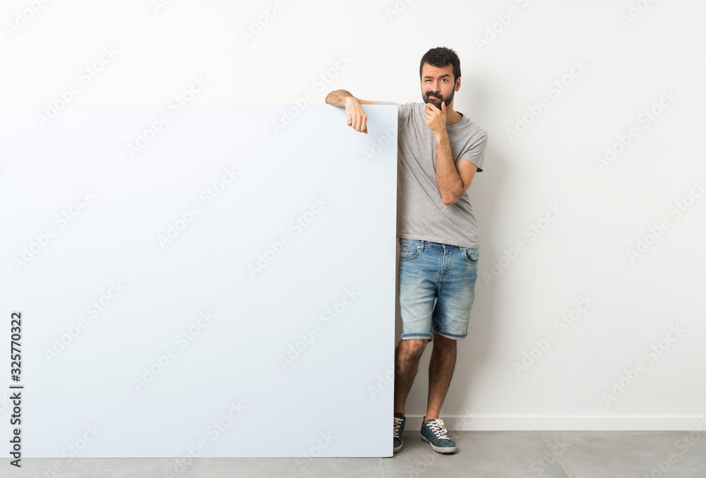 Young handsome man with beard holding a big blue empty placard thinking
