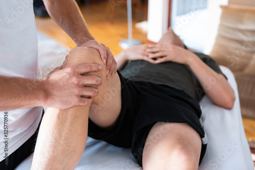 Unrecognizable physiotherapist man massaging legs of a strong muscular man. Masseur working. Massaging leg of man on the massage table in the hospital