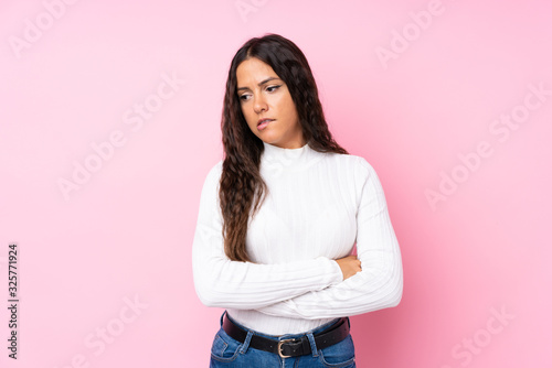 Young woman over isolated pink background with confuse face expression © luismolinero