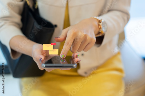 close up businesswoman hand touching on smartphone screen to check email and reply with colleagues for business financial and technology and work for home concept