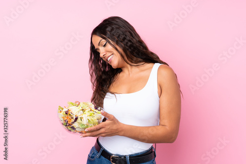 Young woman with salad over isolated wall