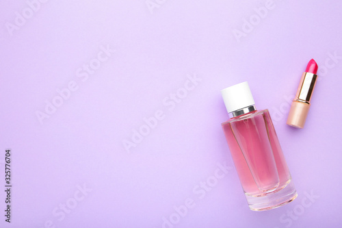 Bottle of perfumes with pink lipstick on lilac background.