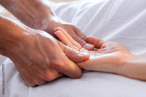 Close-up view of masseur giving relaxing hand massage to a client. Hand massage to a woman in a cosy home environment. Massage and body care photo