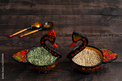 Two wooden painted swan-like dishes. One with wheat, other with medicinal herbs. photo