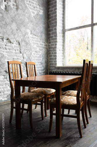 A classic set of wooden furniture for the home. A set of chairs to the table in a loft interior room