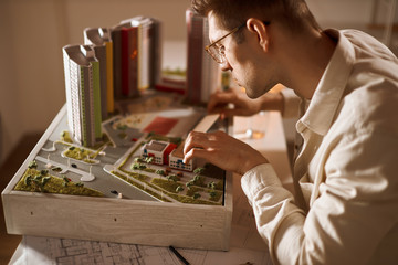 young handsome man developing area, district, close up side view photo. architect working with a ruler and a modele.