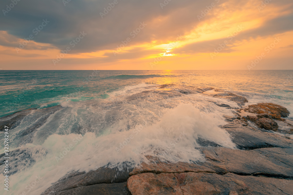 Rocky ocean coast in front of beautiful sunset sky with clouds on Sri Lanka island.