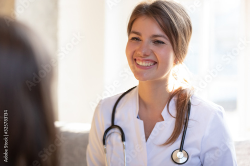 Smiling female doctor with stethoscope listen to patient