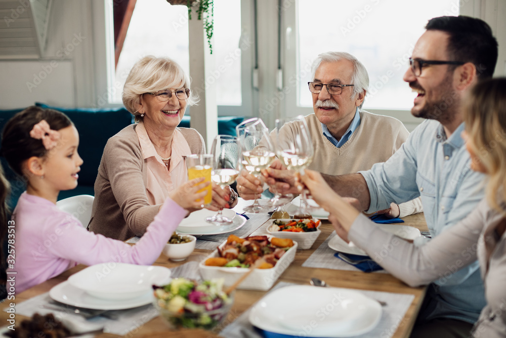 Happy extended family having fun while toasting during lunch at dining table. Happy extended family having fun while toasting during lunch at dining table.