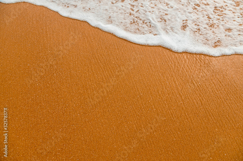 Foam of the ocean surf waves on beach sand.
