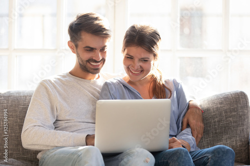 Happy couple relax on couch watching video on laptop