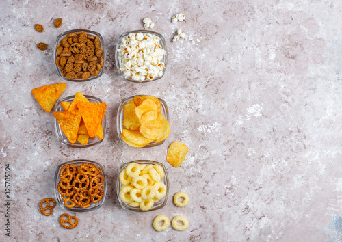 Salty snacks. Pretzels, chips, crackers,popcorn in bowls. Unhealthy products. food bad for figure, skin, heart and teeth. Assortment of fast carbohydrates food