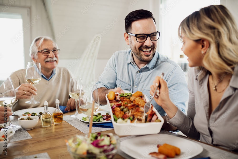 Happy man passing food to his wife during family lunch at dining table. Happy man passing food to his wife during family lunch at dining table.