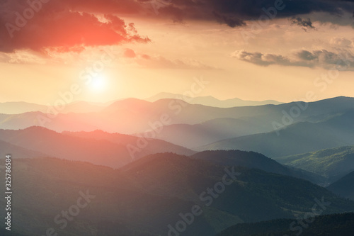 Misty spring mountain hills landscape. Layers of green mountains and hills in the haze during sunset. Concept nature background.