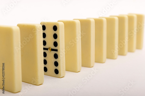 One domino standing out from the row. Domino stones on white backround.