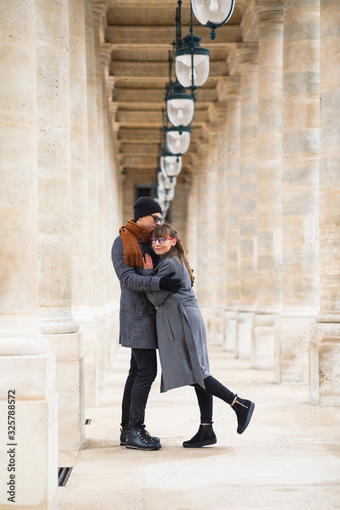 Young beautiful couple dressed stylishly, a girl in a gray coat, a man in a gray coat stand on a square in Paris France