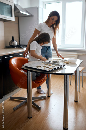 little cute kid learning to cut cookies in the kitchen with modern interior, close up photo. child learning to bake dessert on christmas, holiday
