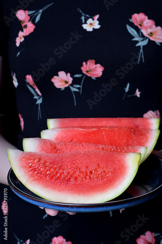 Slices of the Brazilian mini watermelon on the plate in woman hands