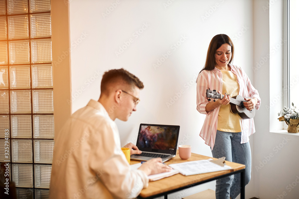 smiling awesome talented brunette girl is disturbing her boyfriend who is preparing for exams. close up photo. family making up melody smiling awesome talented brunette girl is disturbing her boyfriend who is preparing for exams. close up photo. family making up melody
