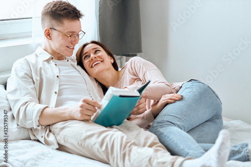 young people get plasure from reading process, family having fun in the bedroom with modern interior. positive feeling and emotion, happiness photo