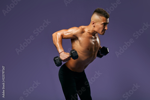 sexy young man developing his stength  close up side view photo  man with tensed body working out at gym . isolated blue background  hobby  interest   lifestyle