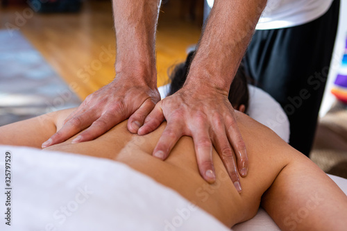 A professional masseur-therapist doing medical massage of sore back of patient. Middle-aged woman receiving therapeutic massage in medical center