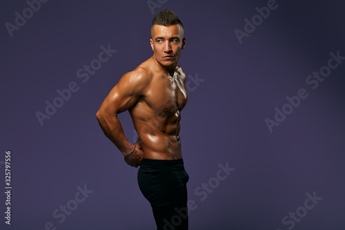 sexy tanned guy with stylish hairdo is being proud of his well-built body  result of active life  close up portrait  man is being on a diet  health care  copy space  isolated blue background