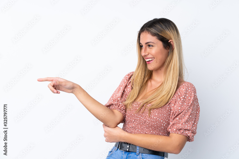 Young Uruguayan woman over isolated white background pointing finger to the side and presenting a product Young Uruguayan woman over isolated white background pointing finger to the side and presenting a product