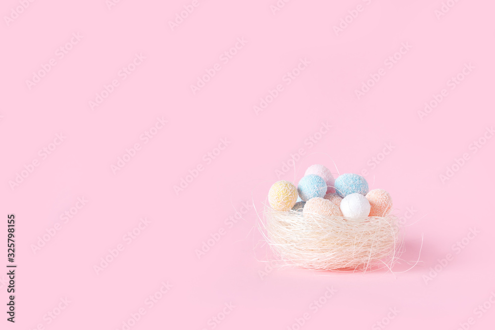 Easter. Nest with multi-colored festive Easter eggs on pink background. Flat lay with copy space.