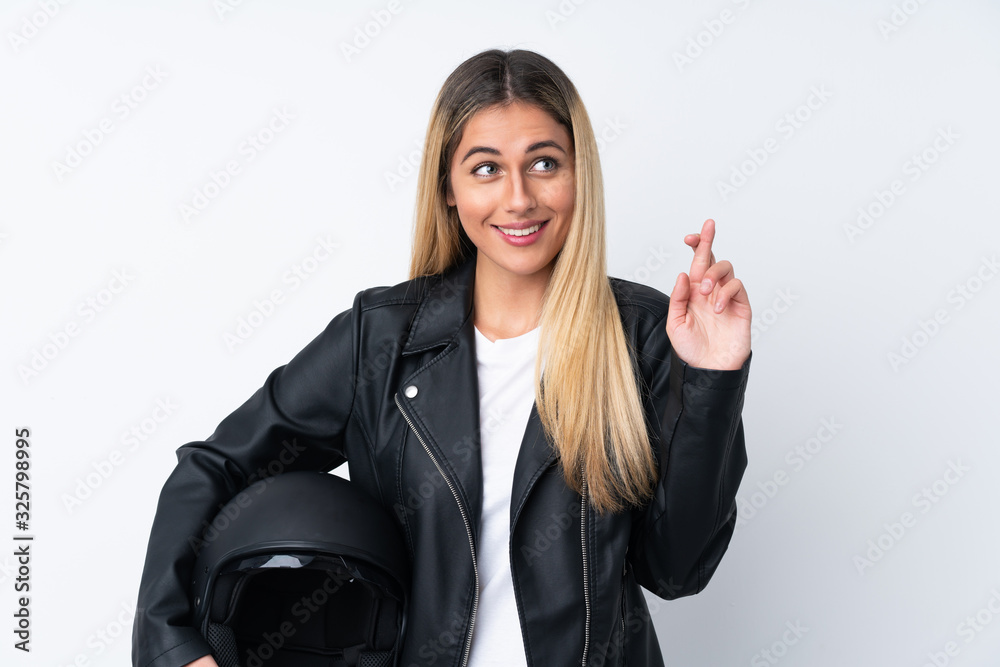 Young Uruguayan woman with a motorcycle helmet over isolated white background with fingers crossing Young Uruguayan woman with a motorcycle helmet over isolated white background with fingers crossing