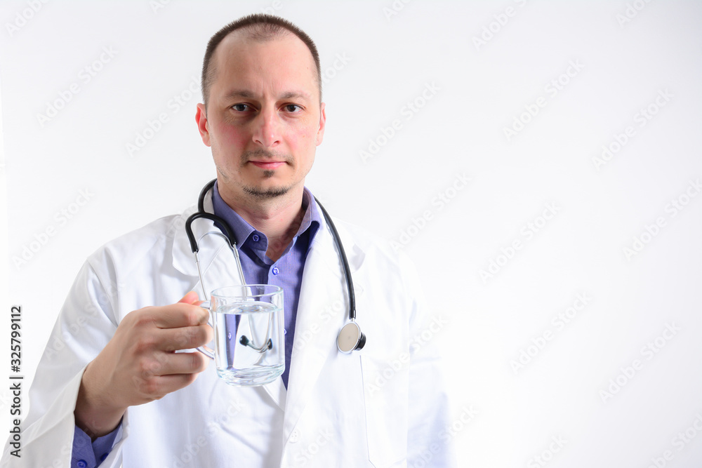 Portrait with copy space of cheerful joyful doctor in white lab coat and stethoscope on his neck, having a glass of water, looking at camera, isolated on grey background. Portrait with copy space of cheerful joyful doctor in white lab coat and stethoscope on his neck, having a glass of water, looking at camera, isolated on grey background.