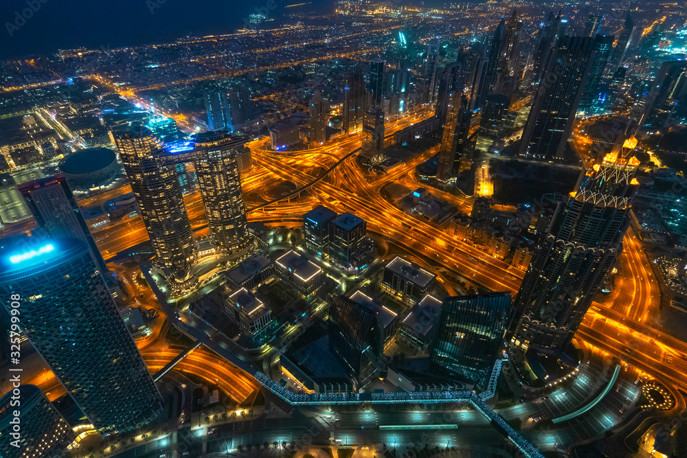 Dubai downtown at night scene with high buildings, towers and illuminated roads, UAE, luxurious travel and tourism.