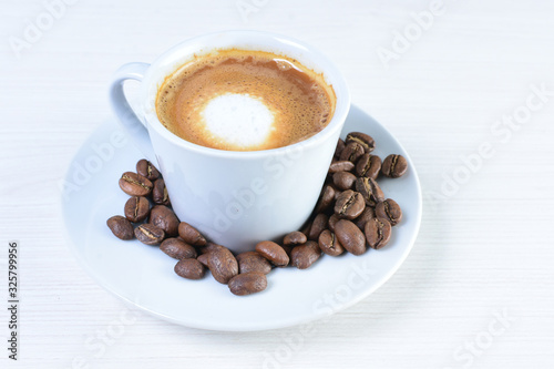 Maquiatto coffee cup with coffee beans on white wooden background