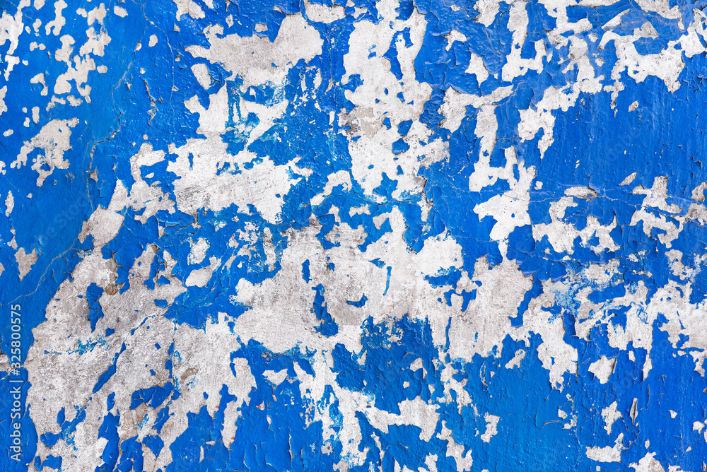 Old cracked paint on a concrete wall. Peeling blue paint on the wall. Texture, pattern, background.