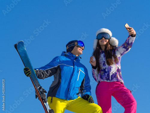Loving couple making winter selfie on a mountain peak.