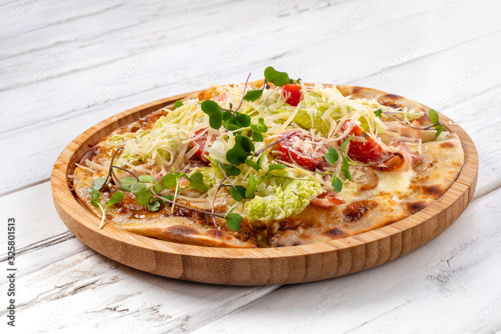 Italian pizza Caesar with chicken and bacon on a white wooden background..