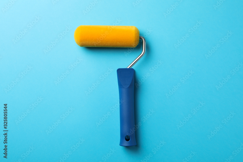 Paint roller on blue background, space for text Paint roller on blue background, space for text