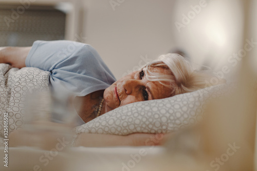 Schilderij op canvas Sleepless mature woman lying in the bed.