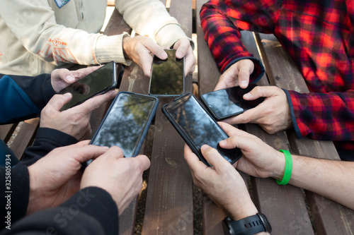 group of friends manipulating mobile phones at a picnic table photo