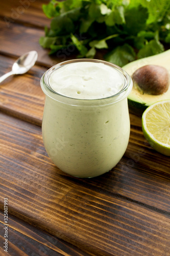 Sauce with yogurt, avocado, lime and cilantro on the brown wooden background. Location vertical.Closeup.