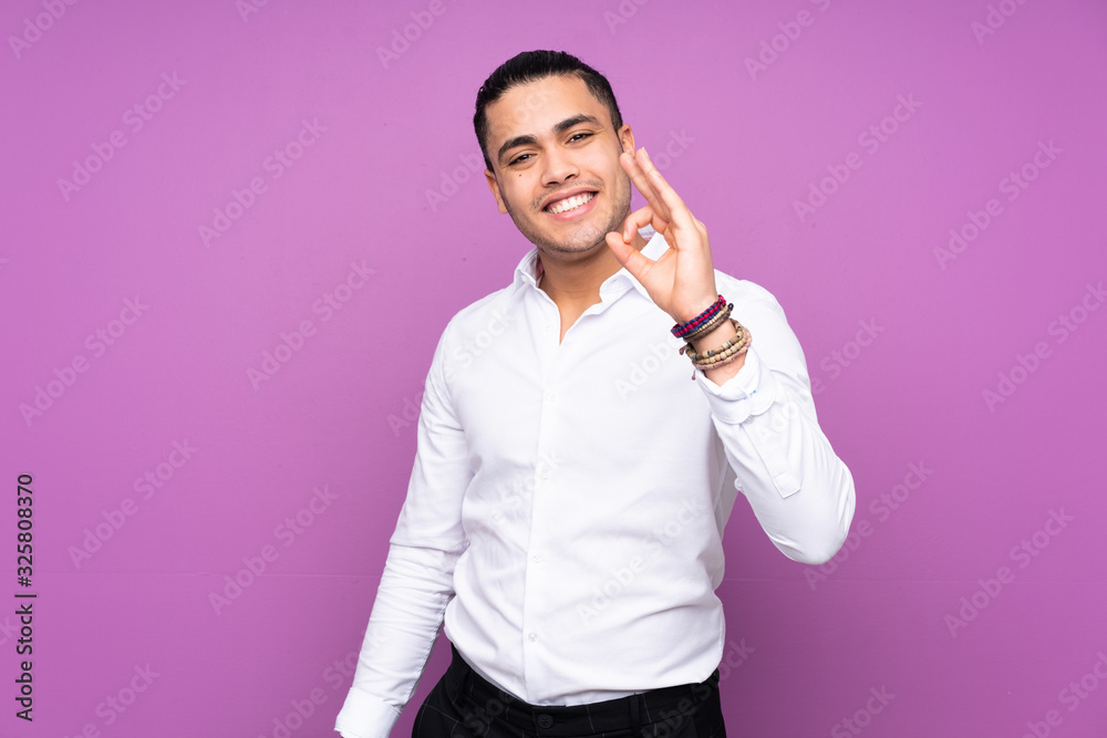 Asian handsome man isolated on blue background showing ok sign with fingers Asian handsome man isolated on blue background showing ok sign with fingers