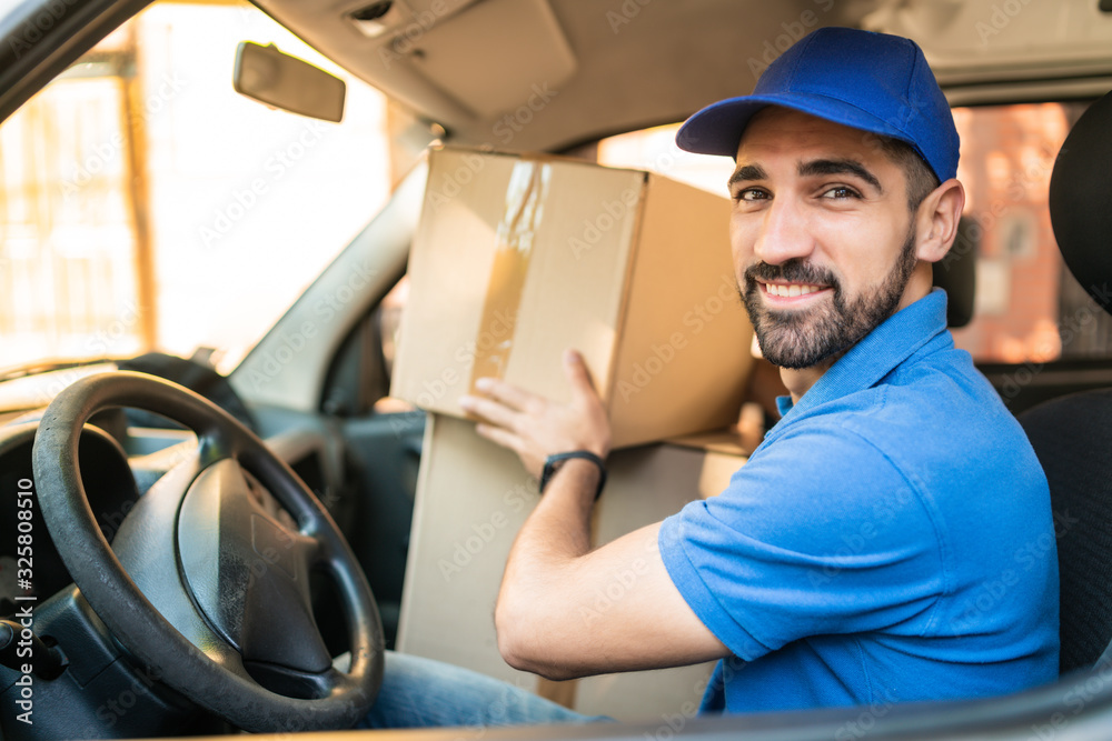 Delivery man driving van with cardboard boxes on seat. Delivery man driving van with cardboard boxes on seat.