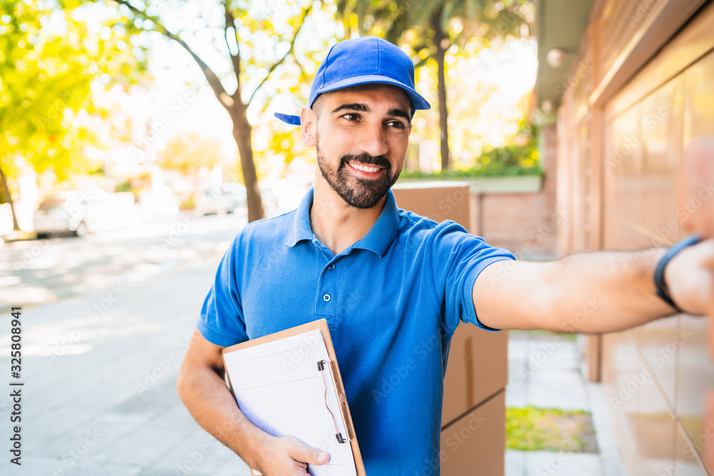Fototapeta premium Delivery man carrying packages while making home delivery.