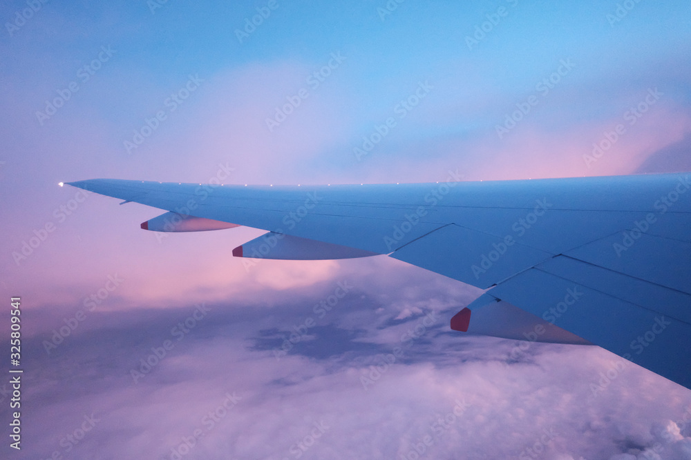 Colorful fluffy clouds and dawn sky with blurred an airplane wing and beautiful high view from a plane window Colorful fluffy clouds and dawn sky with blurred an airplane wing and beautiful high view from a plane window