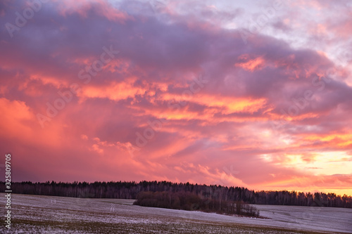 The colorful evening sky is painted with the rays of the setting sun over the forest.