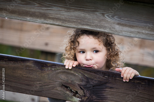 portrait of a little girl on a wooden fence